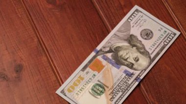 Yeni temiz 100 $'lık banknotlar siyah ahşap bir masanın üzerine serildi.