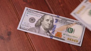 Yeni temiz 100 $'lık banknotlar siyah ahşap bir masanın üzerine serildi.