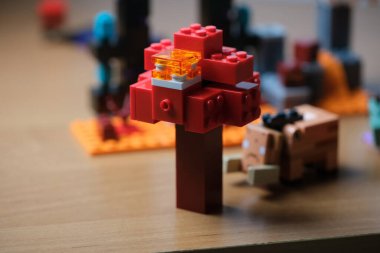 Parlak bloklardan yapılmış neşeli bir ağaç sevimli bir yaratığın yanında duruyor..