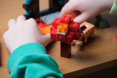 Bir çocuk canlı LEGO parçalarını yaratıcı bir tasarıma dönüştürüyor, gülümsüyor..