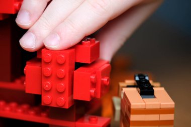 Eller kırmızı yapı taşları kullanarak canlı bir yapı inşa eder..