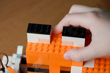 Bir el dikkatle tuğladan yapılmış canlı bir yapıya bir blok yerleştirir..