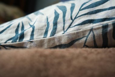 Yapraksı desenlerle süslenmiş yumuşak kumaş sıcak kahverengi bir yüzeye dayanır..