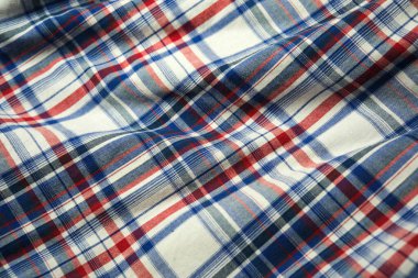 Yumuşak bir kumaş örtüsü zengin renklerde canlı bir ekoseli desen sergiler.