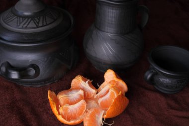 Siyah çömlek kapları sanatsal olarak soyulmuş portakalla sıralanmış..