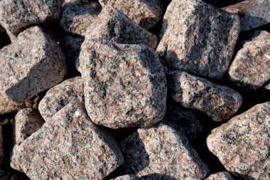 Sert granit taşlar etrafa saçılmış, sıcak güneş ışığı altında parlıyordu..