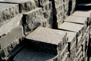 İnşaat alanında düzgünce istiflenmiş taşlar üzerinde gün ışığı parıldıyor..
