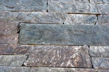 Kalıplı taştan bir duvarın yakın plan görüntüsü ışıkta çeşitli renkler gösterir.