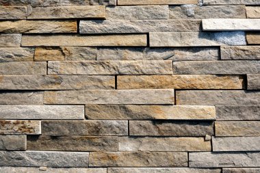 Zengin renk ve dokuları gösteren taştan bir duvarın yakın plan görüntüsü.