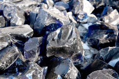 Parlayan siyah ve mavi kristaller kayalık bir arazide güneş ışığını yakalıyorlar..