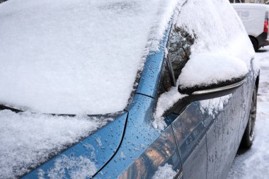 Yoğun kar serin bir günde dışarıda park etmiş parlak mavi bir arabayı kaplıyor..