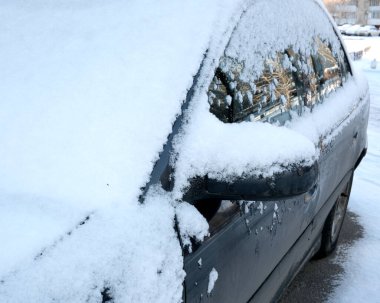 Park halindeki bir araba kış günü kalın kar tabakalarıyla kaplıdır..