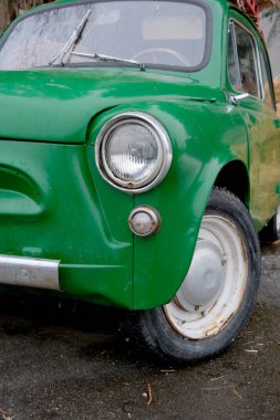 Klasik yeşil bir araç ıslak asfalta karşı duruyor, nostalji uyandırıyor..