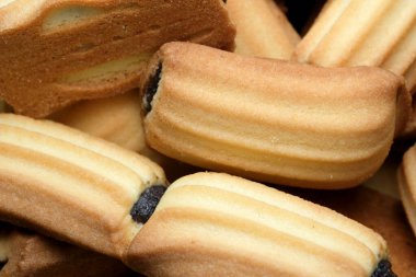 Çeşitli tereyağlı kurabiyelerin yakın plan görüntüsü onların karmaşık dokularını ve davetkar şekillerini ortaya çıkarır. Sıcak renkler ve enfes tasarım eğlenceye hazır bir ziyafet sunar..