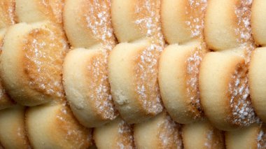 Taze pişmiş tatlı börekler yakın planda oturur, yumuşak, altın kabuklarını sergilerler. Narin tabakalar hafif şekerle kaplanmış, sıcak ve rahatlatıcı bir his uyandırıyor..