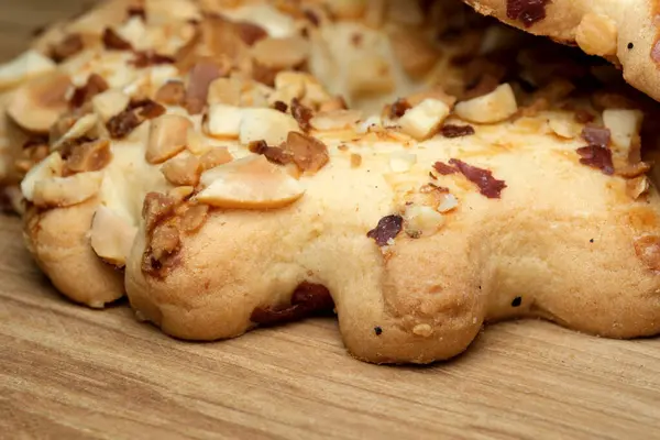 Altın-kahverengi kurabiyeler bir araya toplanmış, çıtır çıtır fındıklı malzemelerle süslenmiş, kırsal ahşap bir masanın üzerine ustalıkla serilmiş. Onların davetkar aromaları her tatlı için enfes bir ikram sunuyor..