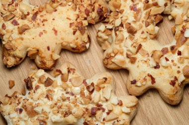 Altın kahverengi oyuncak ayı şekilli kurabiyeler, cömertçe doğranmış fındıklarla kaplı, sıcak ahşap bir yüzeyde dinleniyorlar. Kıtır kıtır dokuları ve enfes aromaları herkese keyifli bir ikram vaat ediyor..