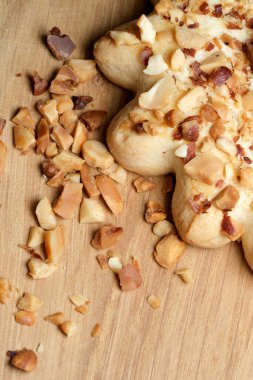 Yıldız şeklinde, doğranmış fındıkla süslenmiş, ahşap bir tahtanın üzerinde duran güzel bir hamur işi. Kırıntılar ve fındıklar etrafa saçılıyor, hoşgörü ve sıcaklığa davetiye çıkarıyorlar..