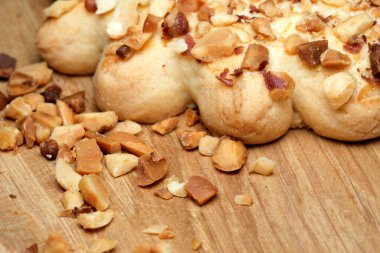 Sıcak ahşap bir yüzeye serpiştirilmiş fındık serpiştirilmiş taze pişmiş hamur işi. Lezzetli aroma ve doku hoş bir mutfak deneyimini davet ediyor..