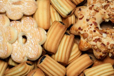 Renkli bir kurabiye dizisi güzel bir şekilde yayılmış, çeşitli şekiller ve dokular sergiliyor. Taze pişmiş ikramın cezbedici kokusu havayı dolduruyor, hoşgörüyü davet ediyor..