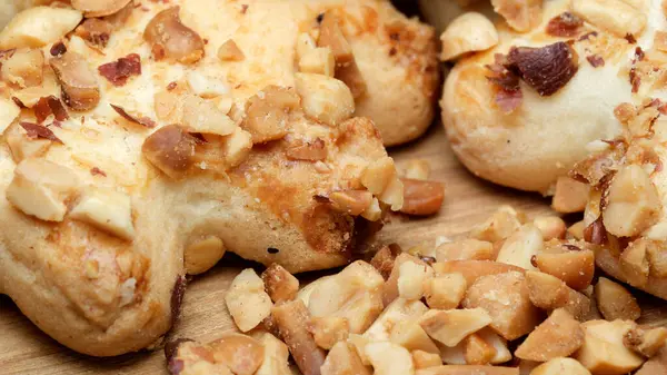 Taze pişmiş hamur parçaları ahşap bir yüzeyde duruyor, cömert bir fındık katmanıyla süslenmiş. Sıcak renkler ve davetkar dokular harika bir aşçılık deneyimi vaat ediyor..