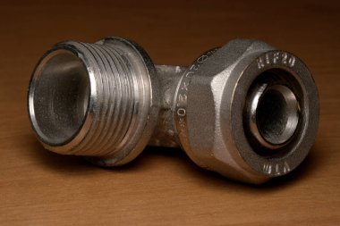 Parlak metalik bir yapı, parlak ahşabın üzerine oturur ve dizaynını ön plana çıkarır..