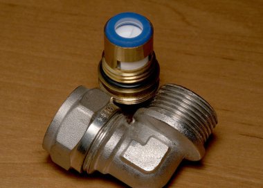 Ahşap bir masada mavi bir yüzükle metal bir tesisat tesisatına yakın plan..