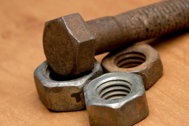 Metal donanım parçaları sıcak ahşap bir yüzeyde gelişigüzel duruyor..