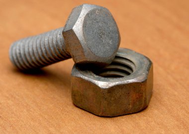 Bir cıvata ve somun, ahşap üzerine güzelce yerleştirilmiş, dokularını sergiliyorlar..