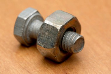 Parlak metal bir cıvata ile ahşap bir fındık birbirine dolanmış..