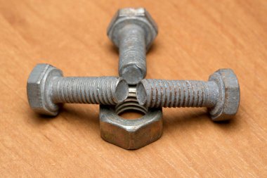 Birkaç metalik cıvata ve bir fındık ahşap bir yüzeye sanatsal olarak yerleştirilmiş..