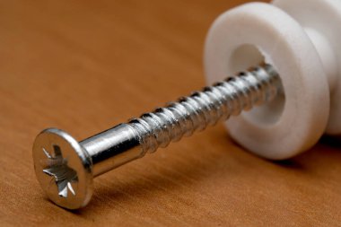 Tahtanın üzerinde beyaz bir boşluk olan metalik vidanın yakın çekim görüntüsü, dokuyu gösterir.