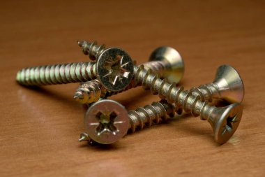 Parlak metal vidalar zarif bir şekilde ahşap arka planda duruyor, ayrıntıları vurguluyor..