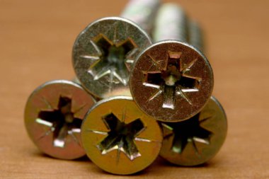 Parlak vidalar sıcak ahşap bir yüzeyde duruyor, detaylarını sergiliyorlar..