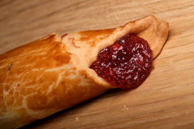 Zengin, tatlı böğürtlen reçeli ile dolu altın kahverengi pasta cezbedici bir ikram sunar.