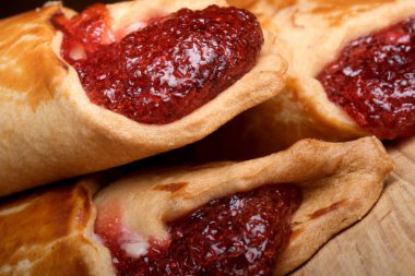 Tatlı çilek reçelli hamur tatlısı ahşap bir yüzeye davetkar bir şekilde oturur..