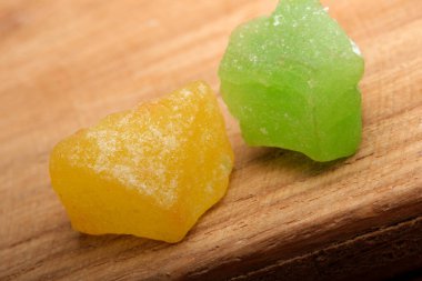 İki canlı şeker parçası, biri sarı ve biri yeşil, ahşap üzerinde dinleniyor..