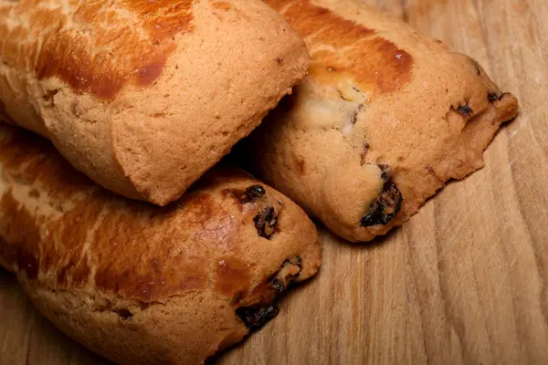 Kuru üzümlerle dolu sıcak, yumuşak hamur işleri tahtadan bir tahtanın üzerinde dinleniyor..