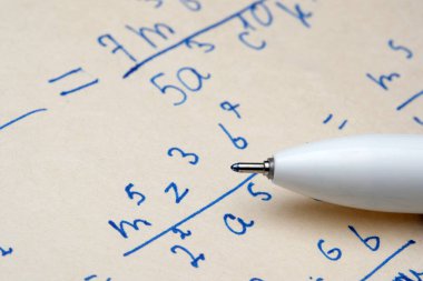 Denklemler üzerinde dinlenen bir kalemle detaylı matematik notlarının yakın görüntüsü.