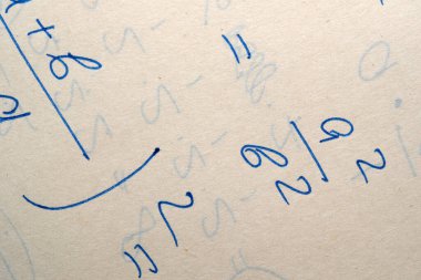 Matematiksel semboller ve sayılar yıpranmış bir kağıt yüzeyi formüllerle doldurur.