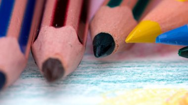 Renkli kalemlerden oluşan canlı bir sıra renkli bir sanat eserinin yanında duruyor..