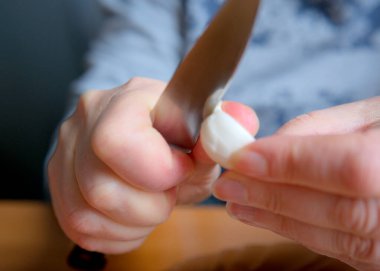 Bir insan yumuşak peyniri ustalıkla ılık ışıkla keser..