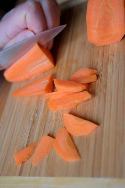 Bir el ustalıkla dilimler taze patatesleri kesme tahtasında.