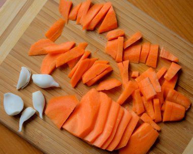 Taze doğranmış havuçlar ahşap bir tahtanın üzerinde, pişirilmeye hazır..