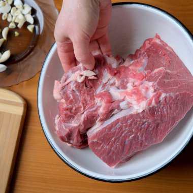 Elle bir parça çiğ eti bir kaseye koyar, pişirmeye hazırdır..