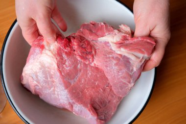 Elleri, büyük bir parça çiğ eti pişirmeye hazır bir kasede tutuyor..