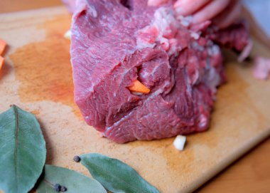 Bir aşçı ustalıkla bir parça çiğ et hazırlar, aromatik sebzeler ekler..