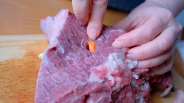 Eller ustalıkla renkli sebzeleri tahtadan yapılmış çiğ bifteğe yerleştirir..