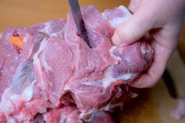 Bir el çiğ eti ustalıkla keser, yemek pişirme becerisini gösterir ve odaklanır..