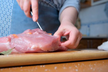 Bir insan ahşap bir tahtada ustalıkla taze et keser, otlarla çevrili..